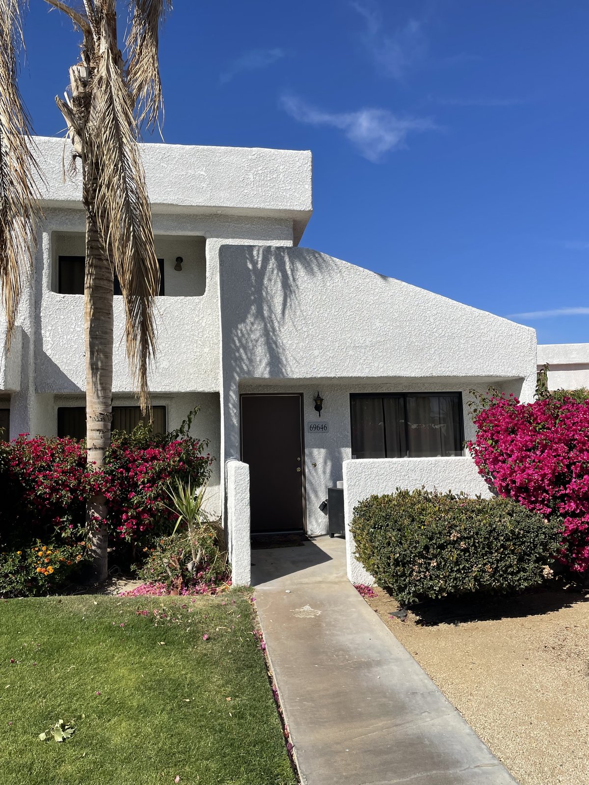 White stucco Orange County condo with bougainvillea and palm trees at the front entry